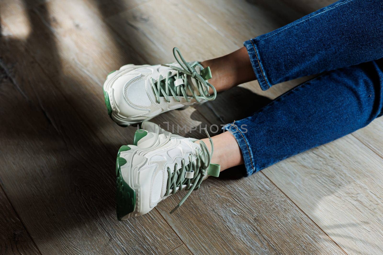 Sports shoes for women. Slender female legs in jeans and white stylish casual sneakers. Comfortable women's summer shoes. Casual women's fashion.