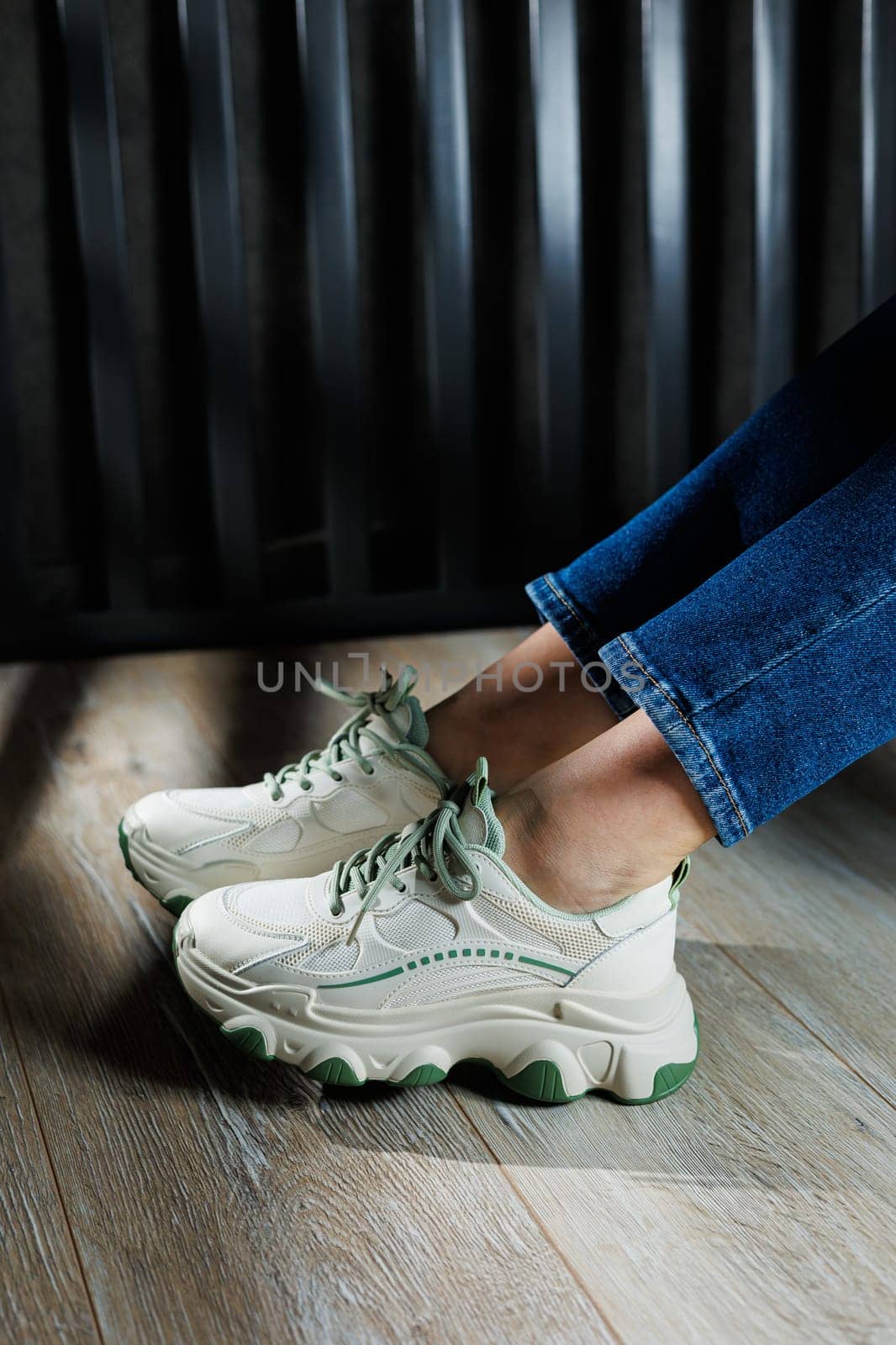 Sports shoes for women. Slender female legs in jeans and white stylish casual sneakers. Comfortable women's summer shoes. Casual women's fashion.