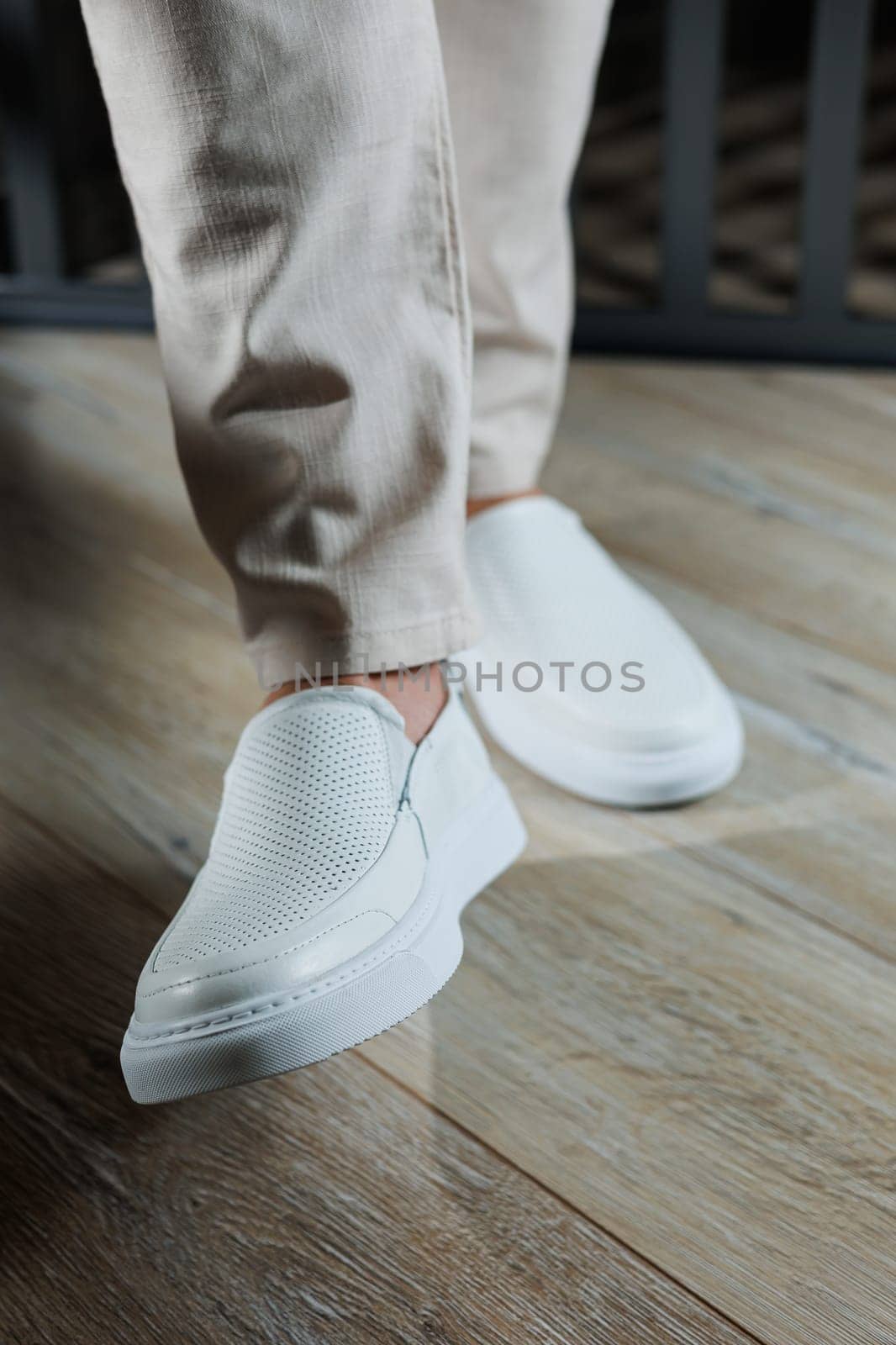 Male legs in leather summer shoes. Comfortable men's white moccasins without laces. Casual men's moccasins
