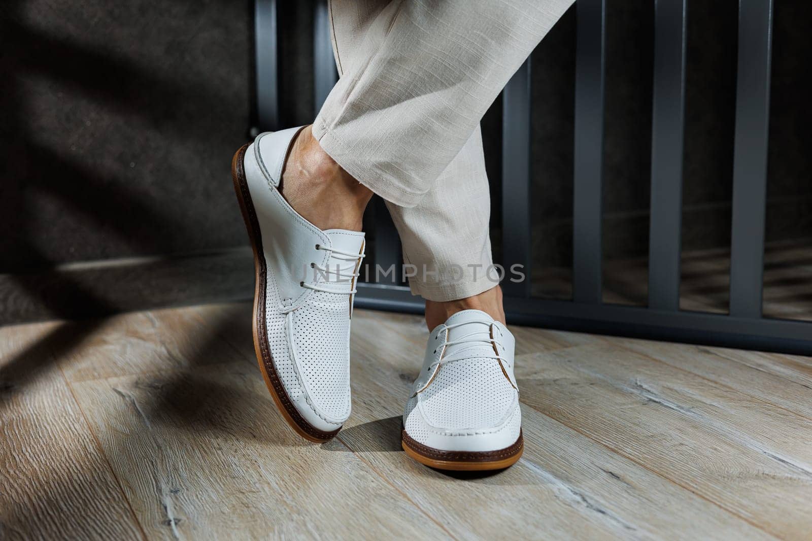 Male legs in leather summer shoes. Comfortable men's white moccasins without laces. Casual men's moccasins