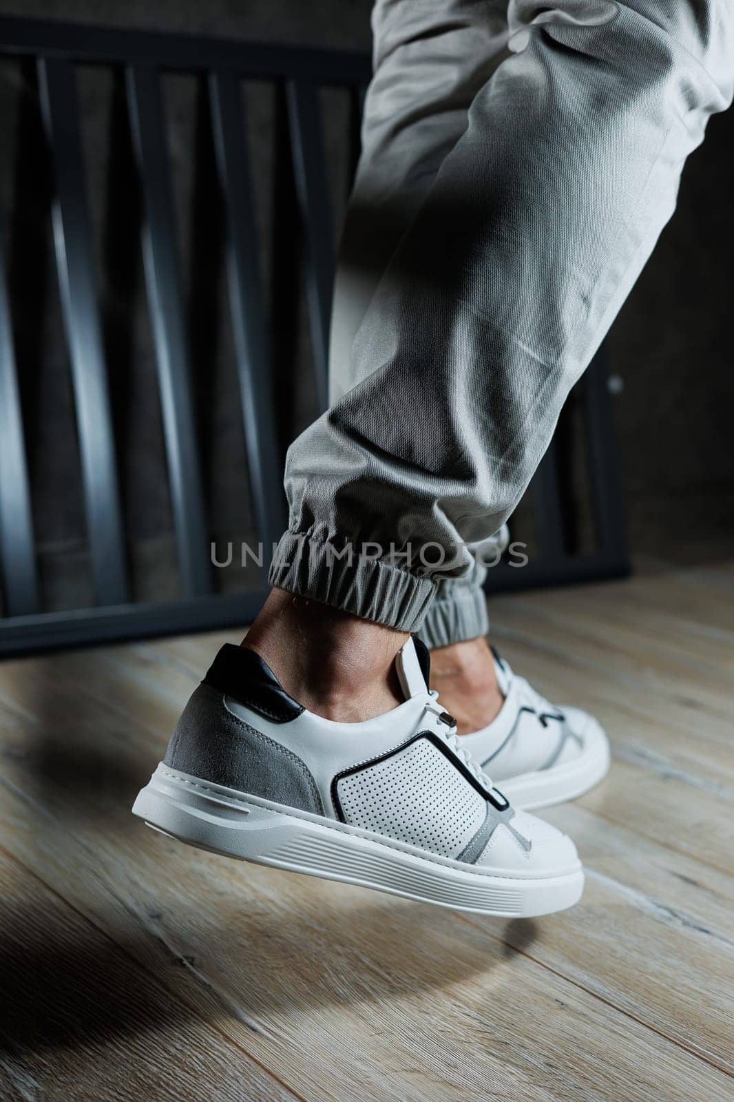 Casual white sneakers for men. Male legs in white leather summer shoes. Comfortable men's white sneakers with laces.