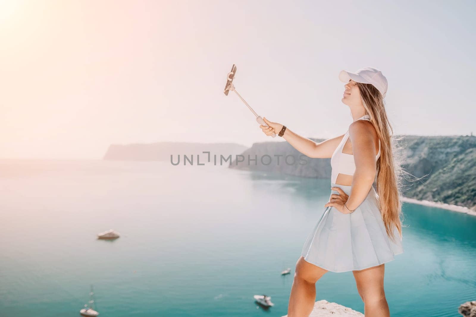 Digital nomad, Business woman working on laptop by the sea. Pretty lady typing on computer by the sea at sunset, makes a business transaction online from a distance. Freelance remote work on vacation