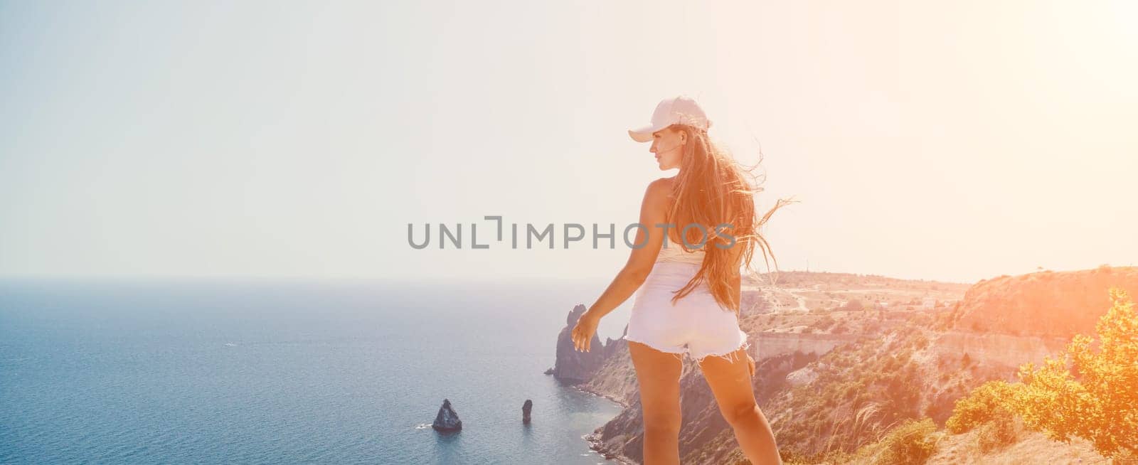 Woman summer travel sea. Happy tourist enjoy taking picture outdoors for memories. Woman traveler posing over sea bay surrounded by volcanic mountains, sharing travel adventure journey by panophotograph