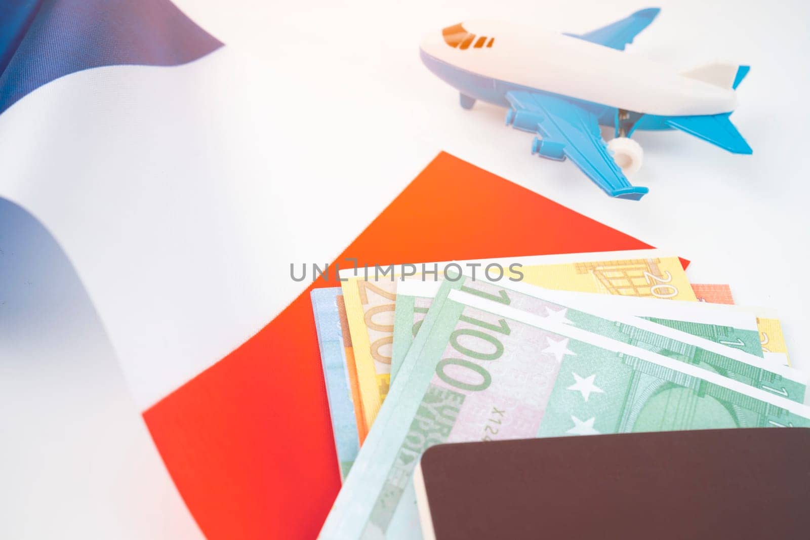 Euro banknotes and passport on France flag with airplane toy. Travel planning concept .