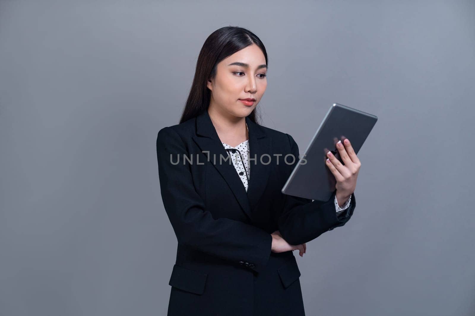 Confident young Asian businesswoman posing with tablet on isolated background. Office lady make hand holding gesture for promotions sales, technology and innovation products advertisements. Jubilant