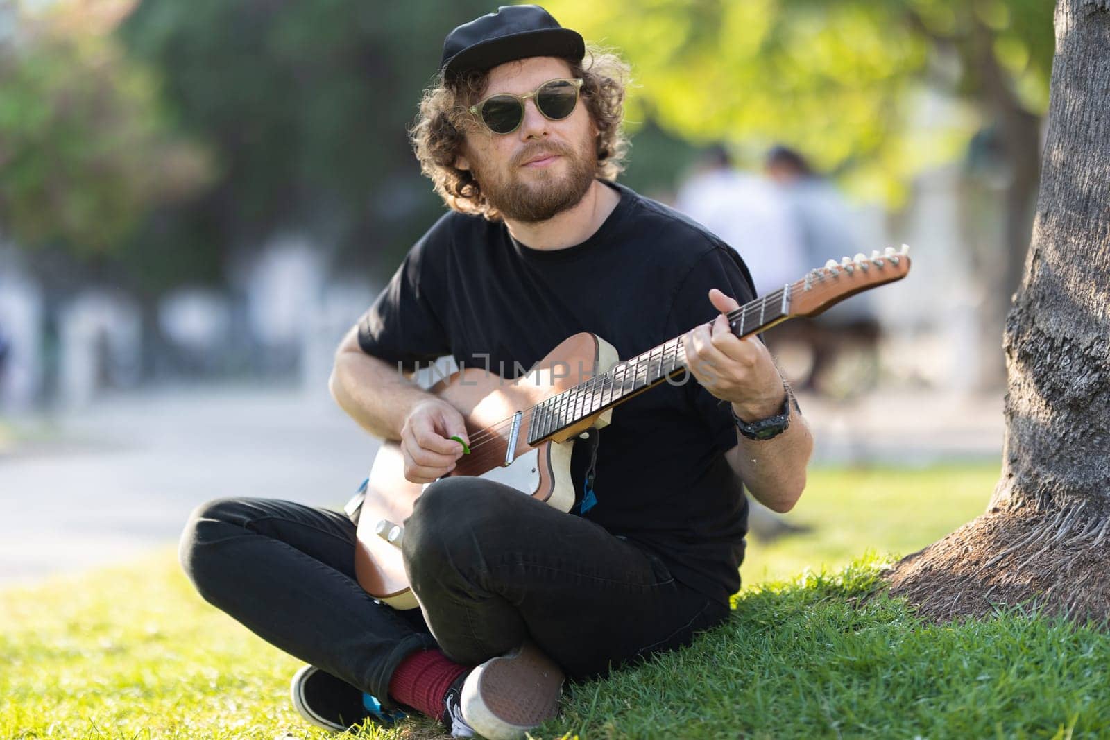 Man playing electric guitar in the park. Mid shot