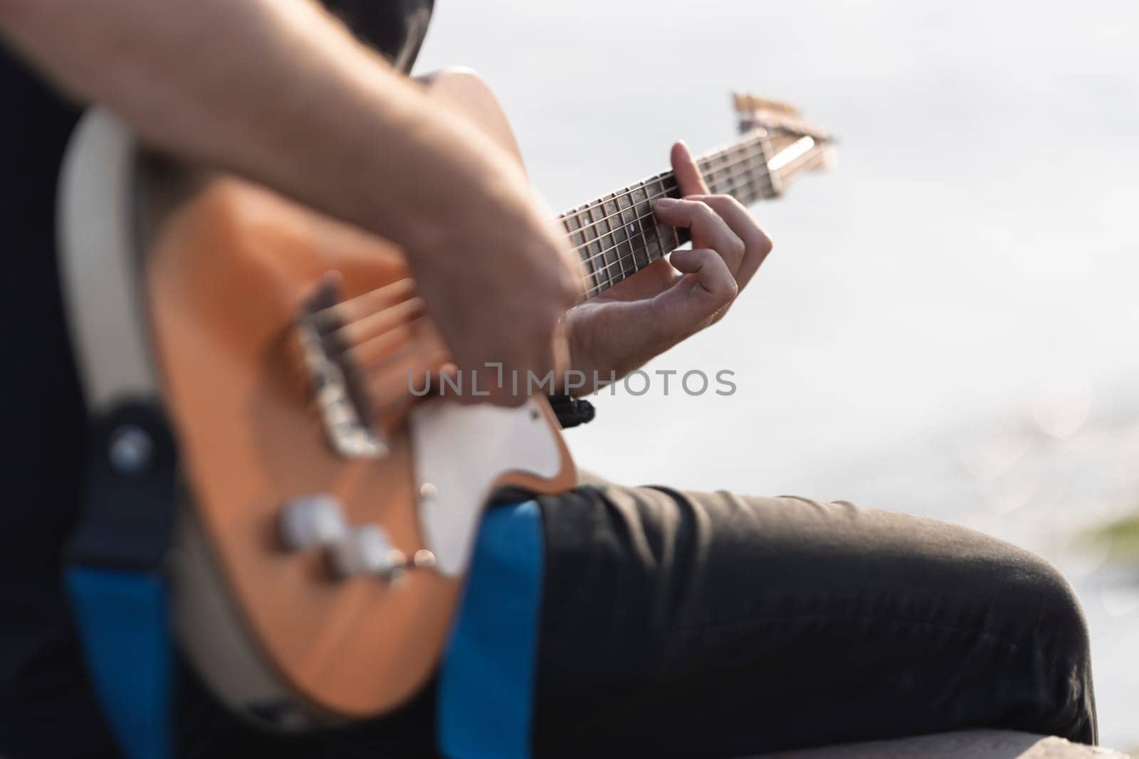 Man playing electric guitar outdoors. Mid shot