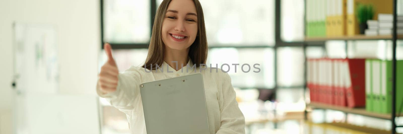 Smiling businesswoman showing ok thumb up in office. Successful career in business concept