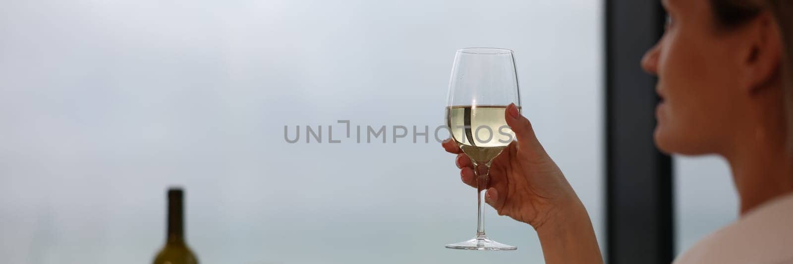 Woman in bathrobe holding glass of white wine closeup. Rest and relaxation in hotel concept