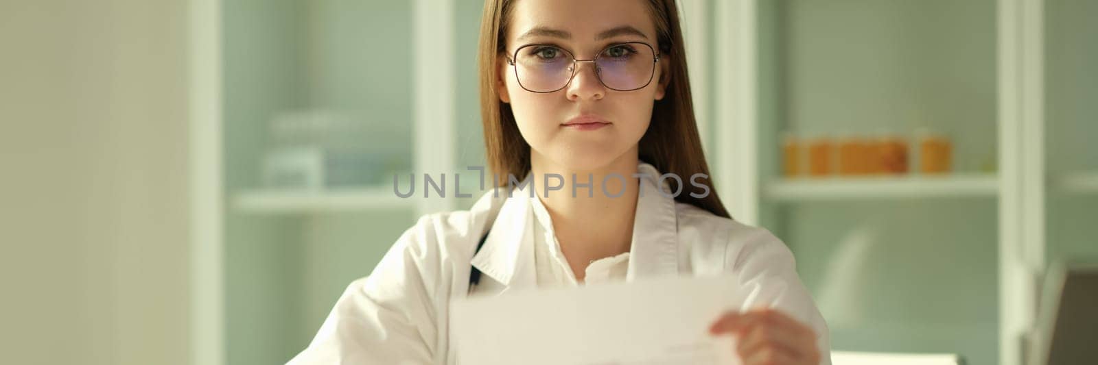 Doctor cardiologist examining patient cardiogram on paper in clinic by kuprevich