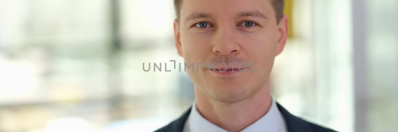 Portrait of young handsome businessman in suit with tie in office by kuprevich