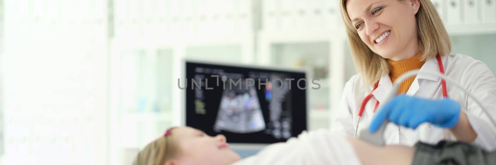 Doctor pediatrician making ultrasound examination of abdominal organs of child in clinic by kuprevich