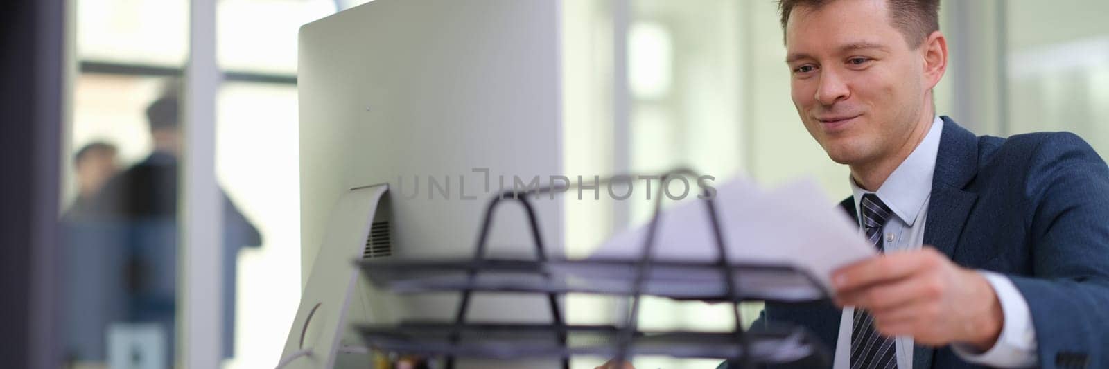 Businessman putting paper documents on stand on table in office. Business paperwork concept