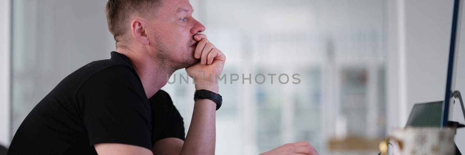 Male freelancer working on computer at home by kuprevich