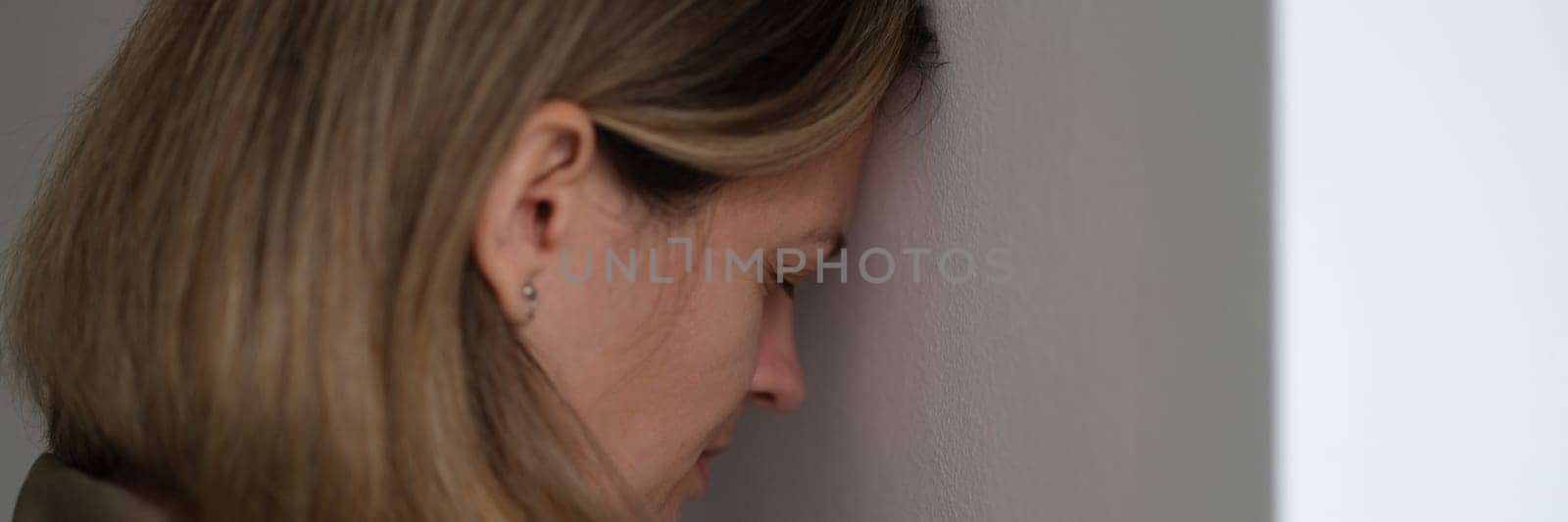 Tired depressed woman banging her head against wall. Hopeless situations concept