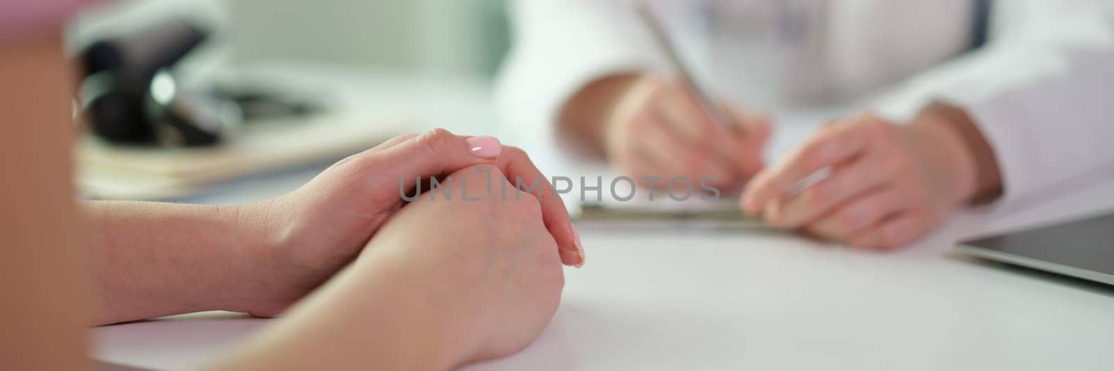 Patient hands on table during visit to doctor in clinic closeup. Medicare concept