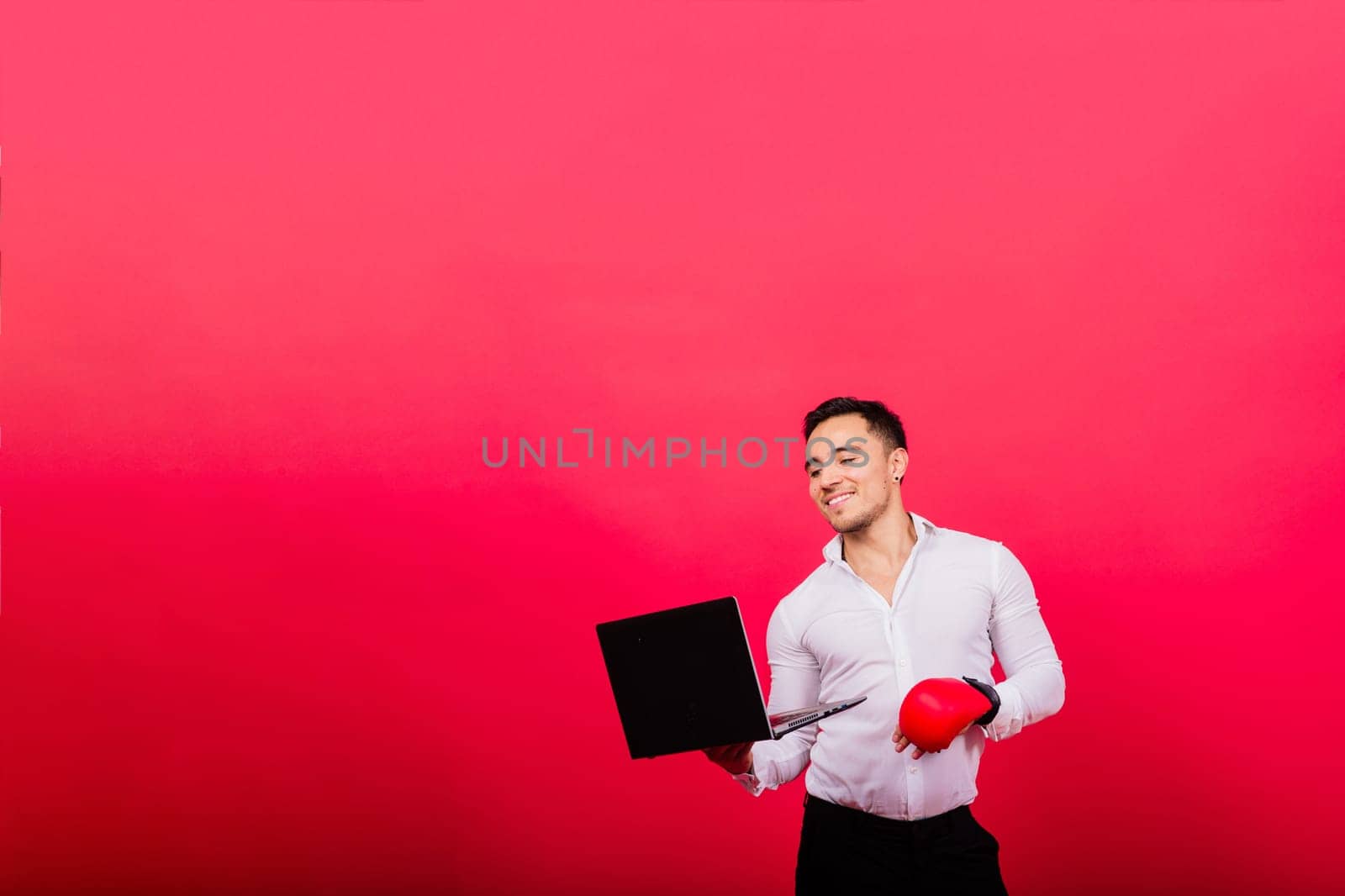 Guy in boxing gloves and formalwear punch computer isolated on a red, cyber bullying.