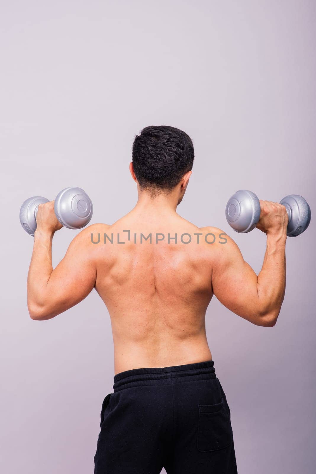 Shirtless bodybuilder showing his great body and holding dumbells.