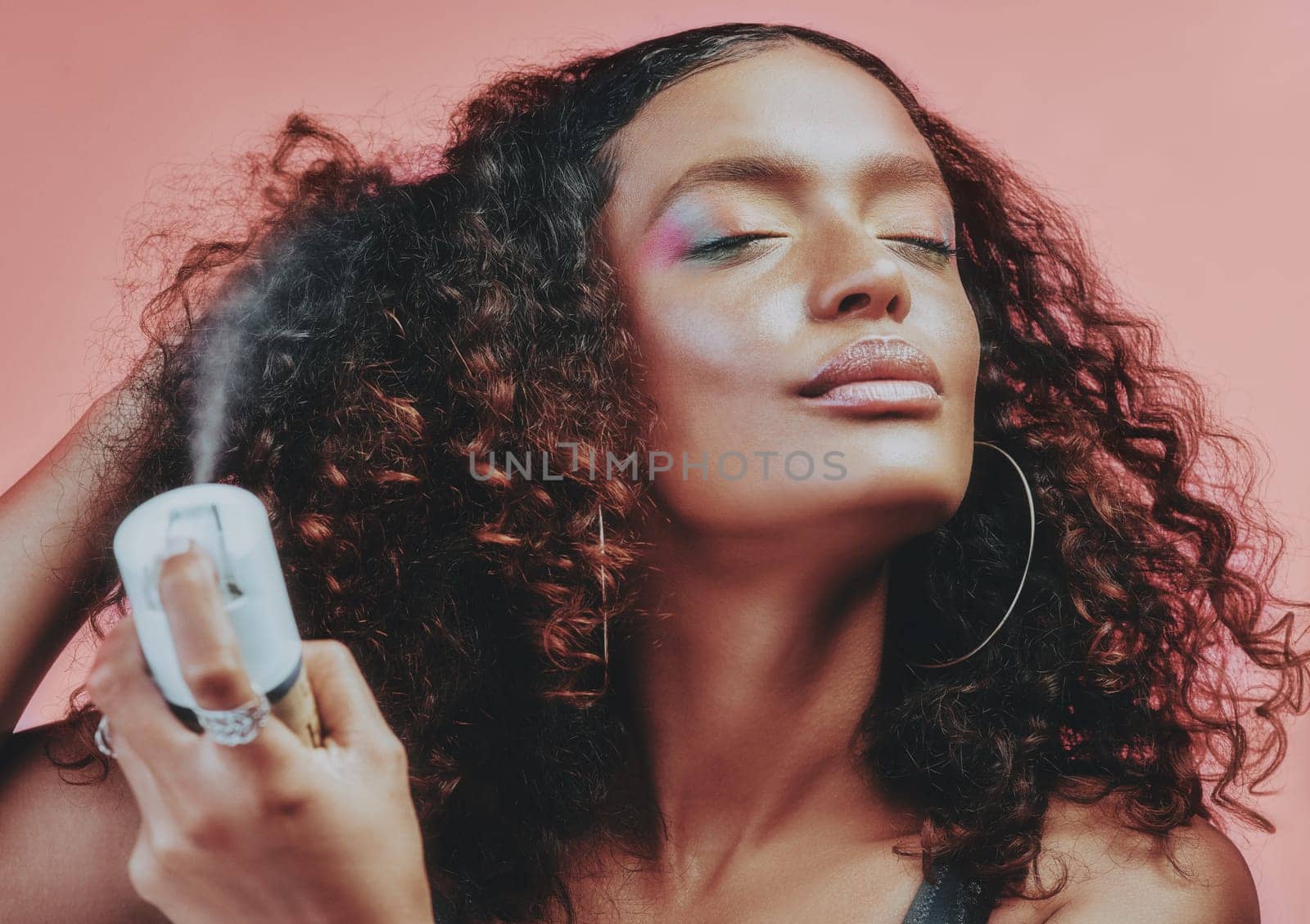 Hairspray, curly hair and beauty with woman in studio for hairstyle, self care and natural. Skincare, makeup and cosmetics with female model isolated on pink background for pride, glow and texture by YuriArcurs