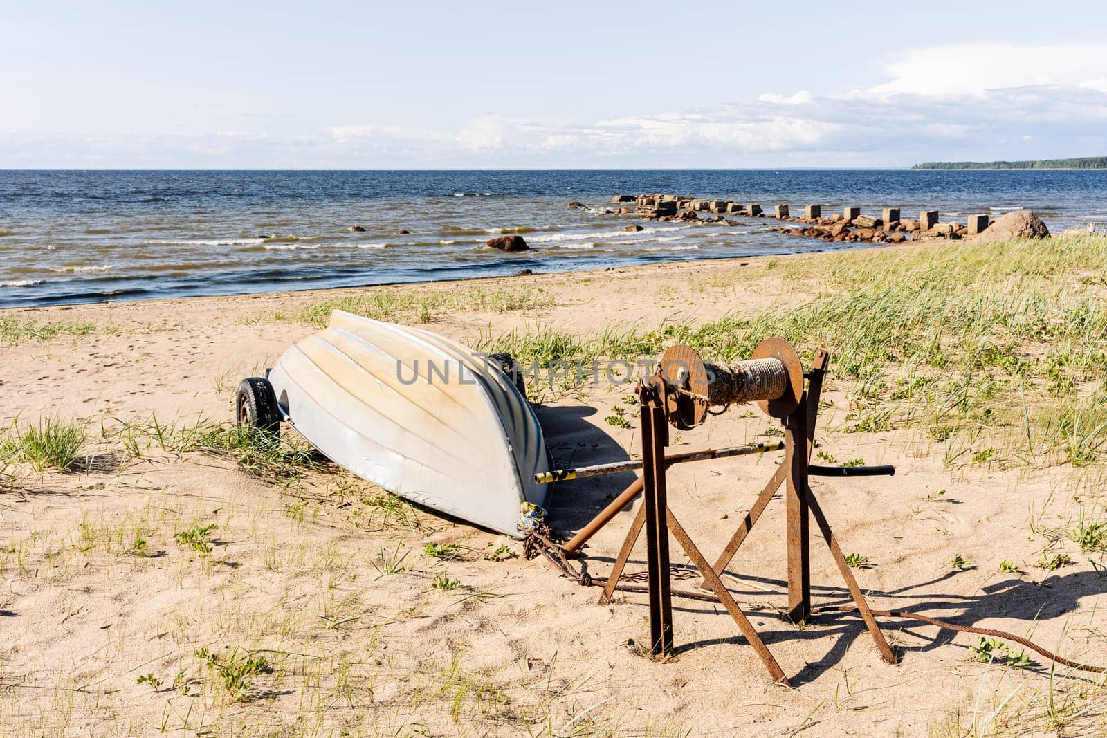 Old fishing boats pulled out on the sandy shore of the sea bay in sunny weather. Fishermen's boats are resting on the shore lying upside down