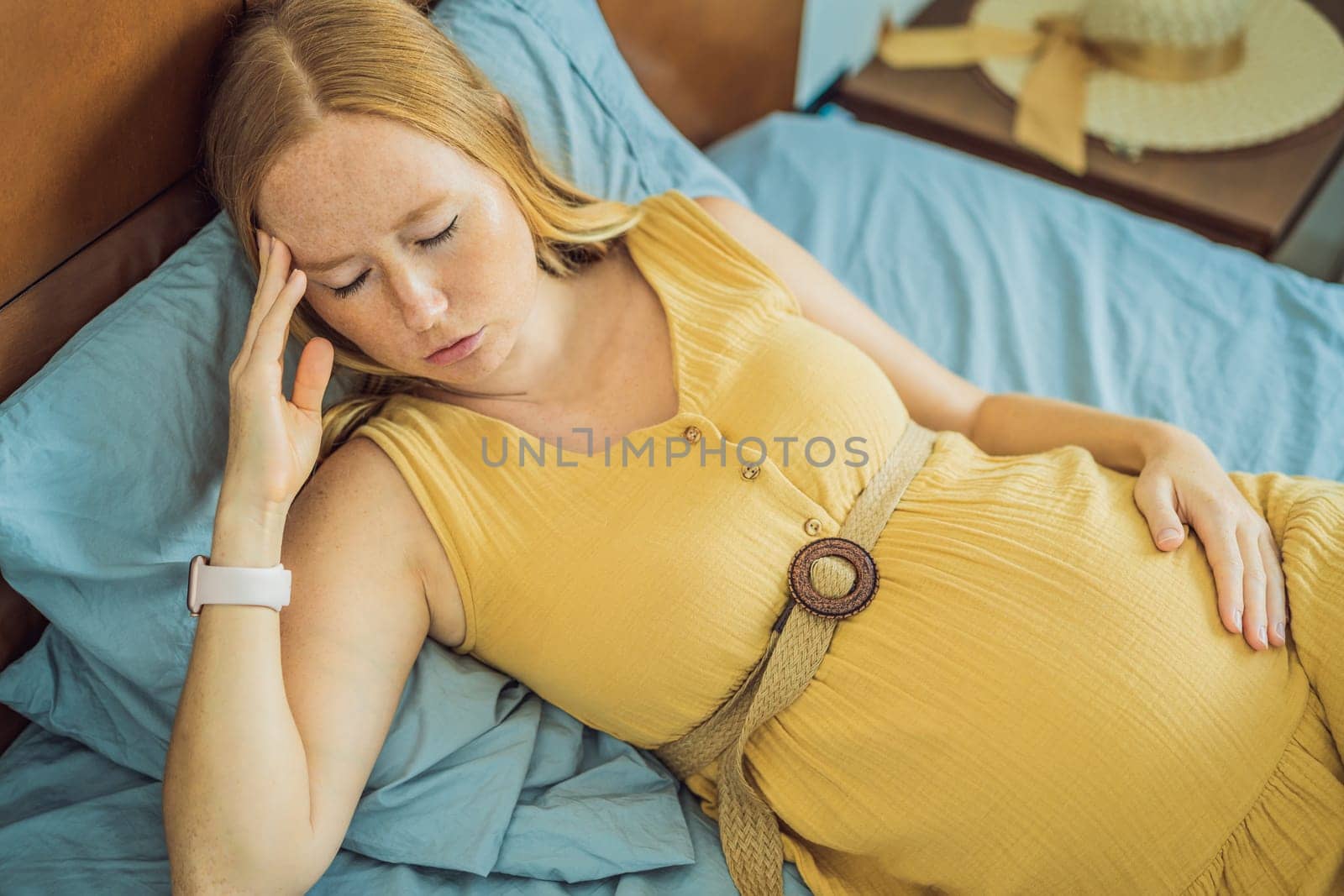 A stressed tired pregnant mother lying in bed at home. Morning sickness and nausea.