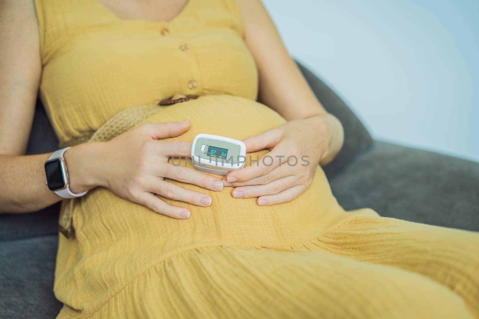 Pregnant woman with pulse oximeter on finger. Doctor measuring oxygen saturation level while visiting expectant mother with coronavirus disease at home, cropped. Pregnancy and covid-19 concept.
