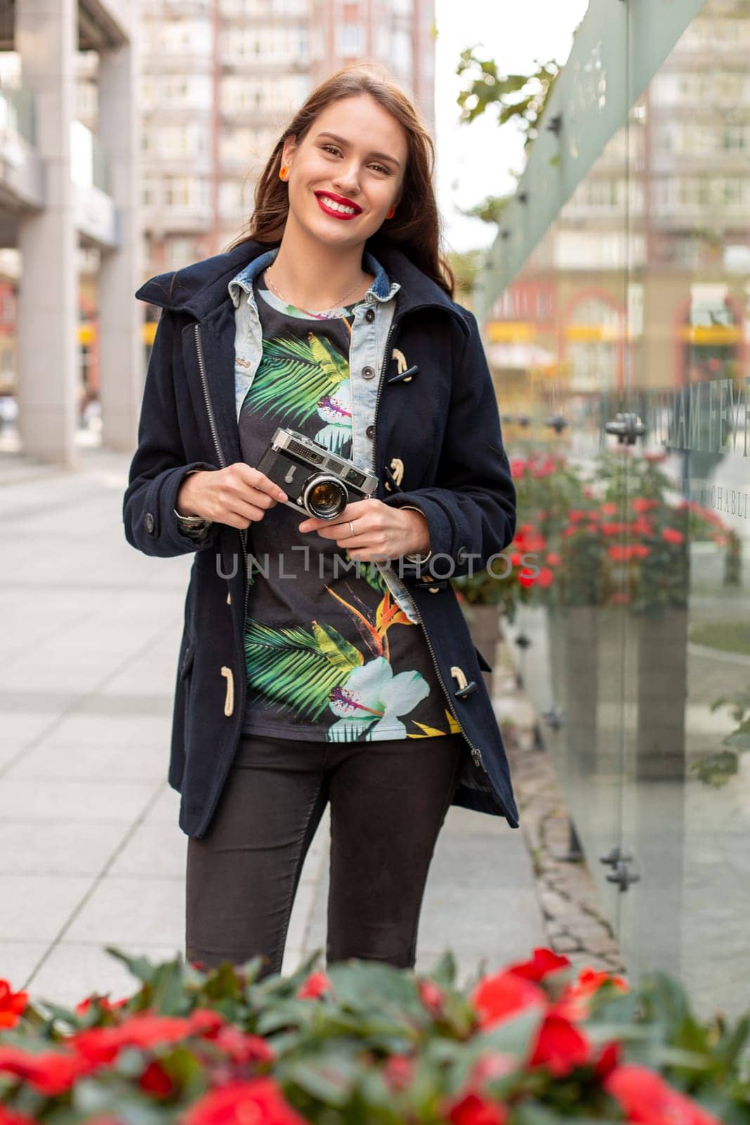 Outdoor autumn smiling lifestyle portrait of pretty young woman, having fun in the city with camera, travel photo of photographer. Making pictures in hipster style.