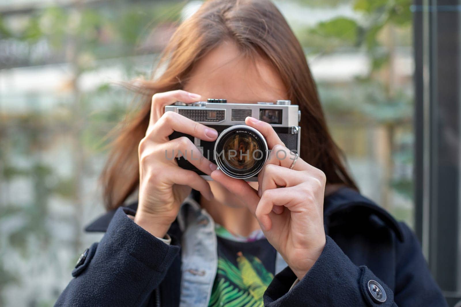 Portrait of a pretty young tourist taking photographs with vintage retro camera. Street style. Life style