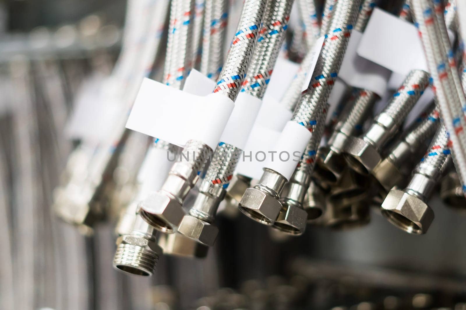 Closed up braided stainless steel texture of flexible hose arranged in row against white wall.