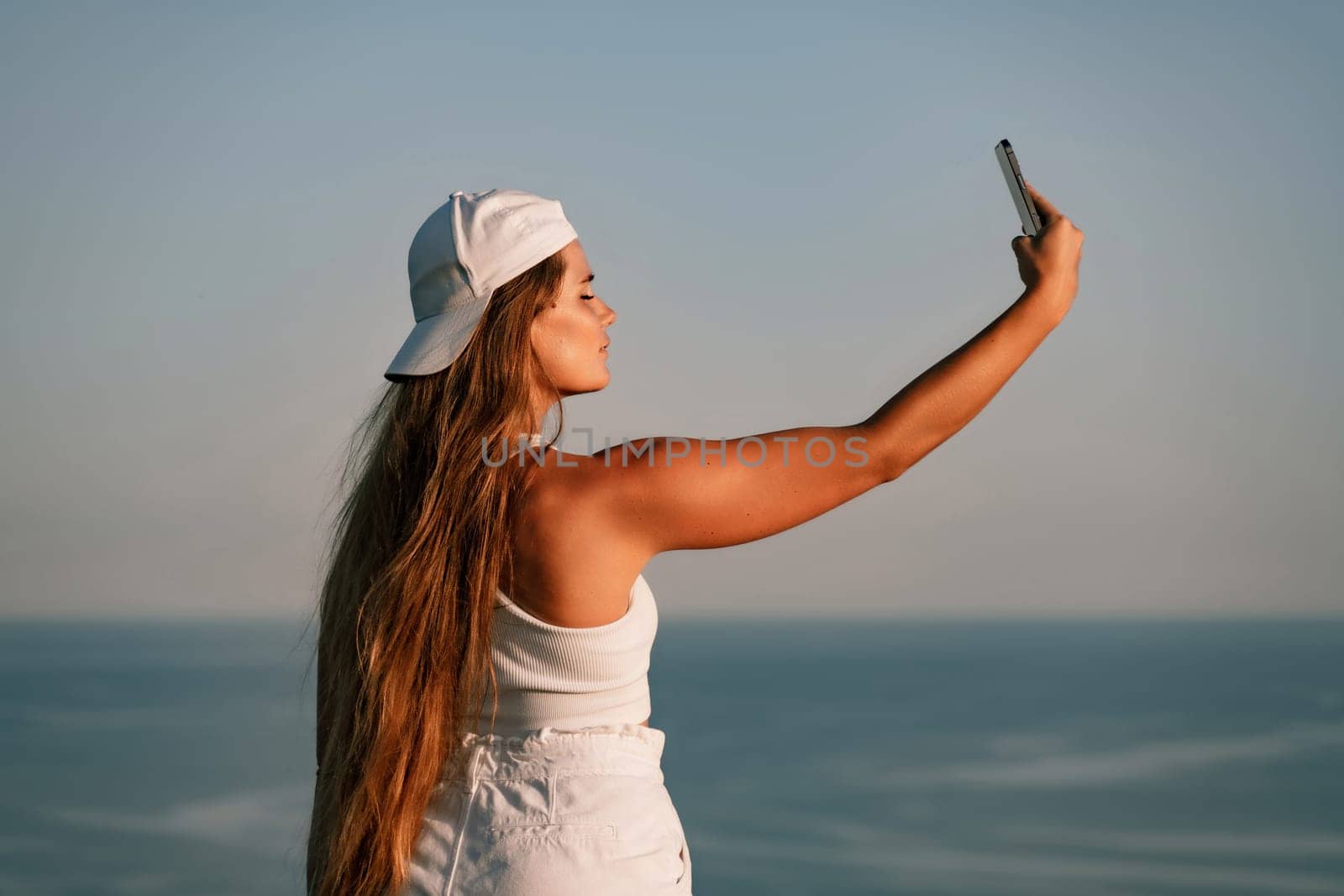 Selfie woman in cap and tank top making selfie shot mobile phone post photo social network outdoors on sea background beach people vacation lifestyle travel concept