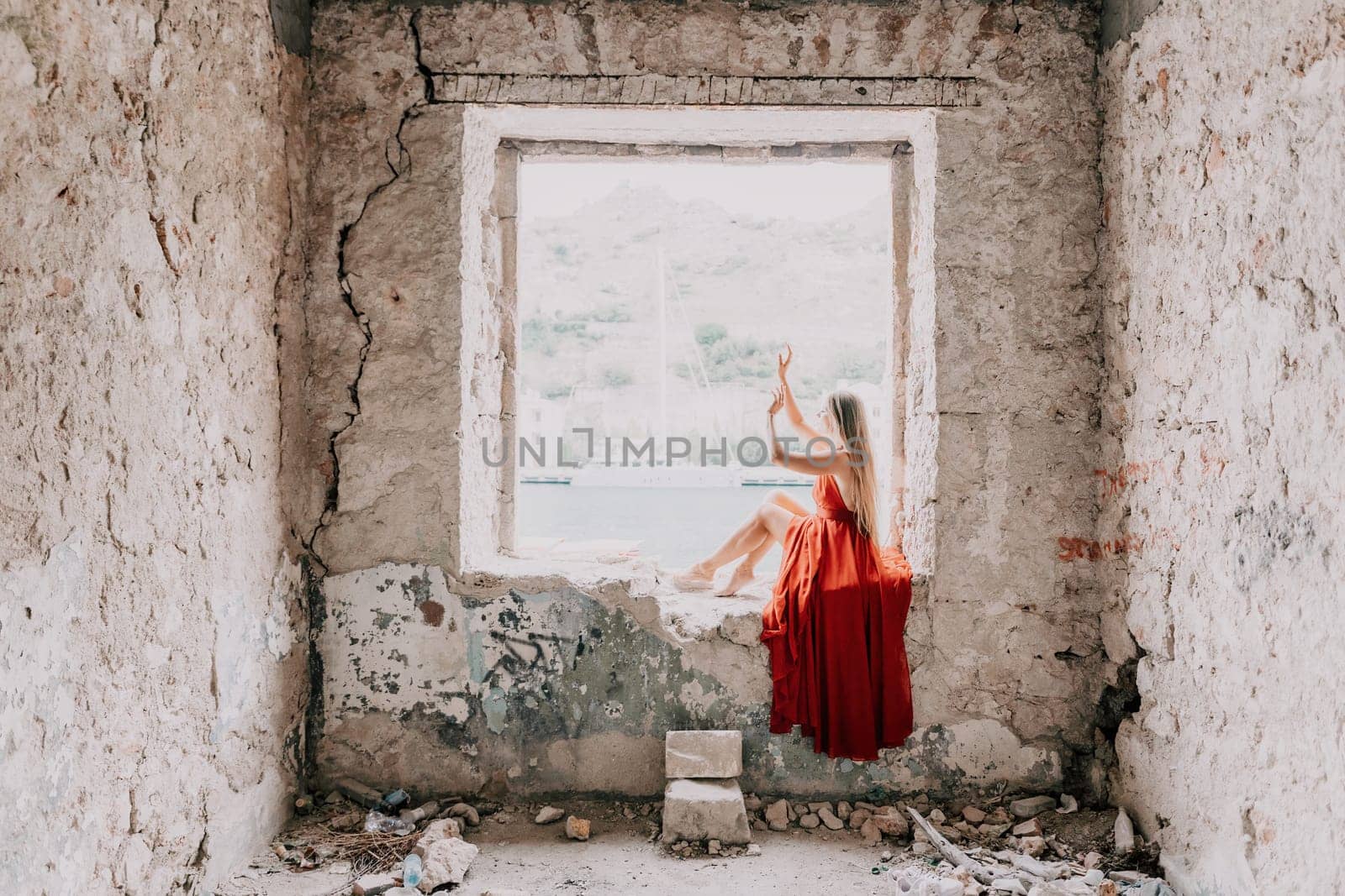 Woman travel portrait. Happy woman with long hair looking at camera and smiling. Close up portrait cute woman in a res long dress posing on backdrop of old travel city near sea by panophotograph