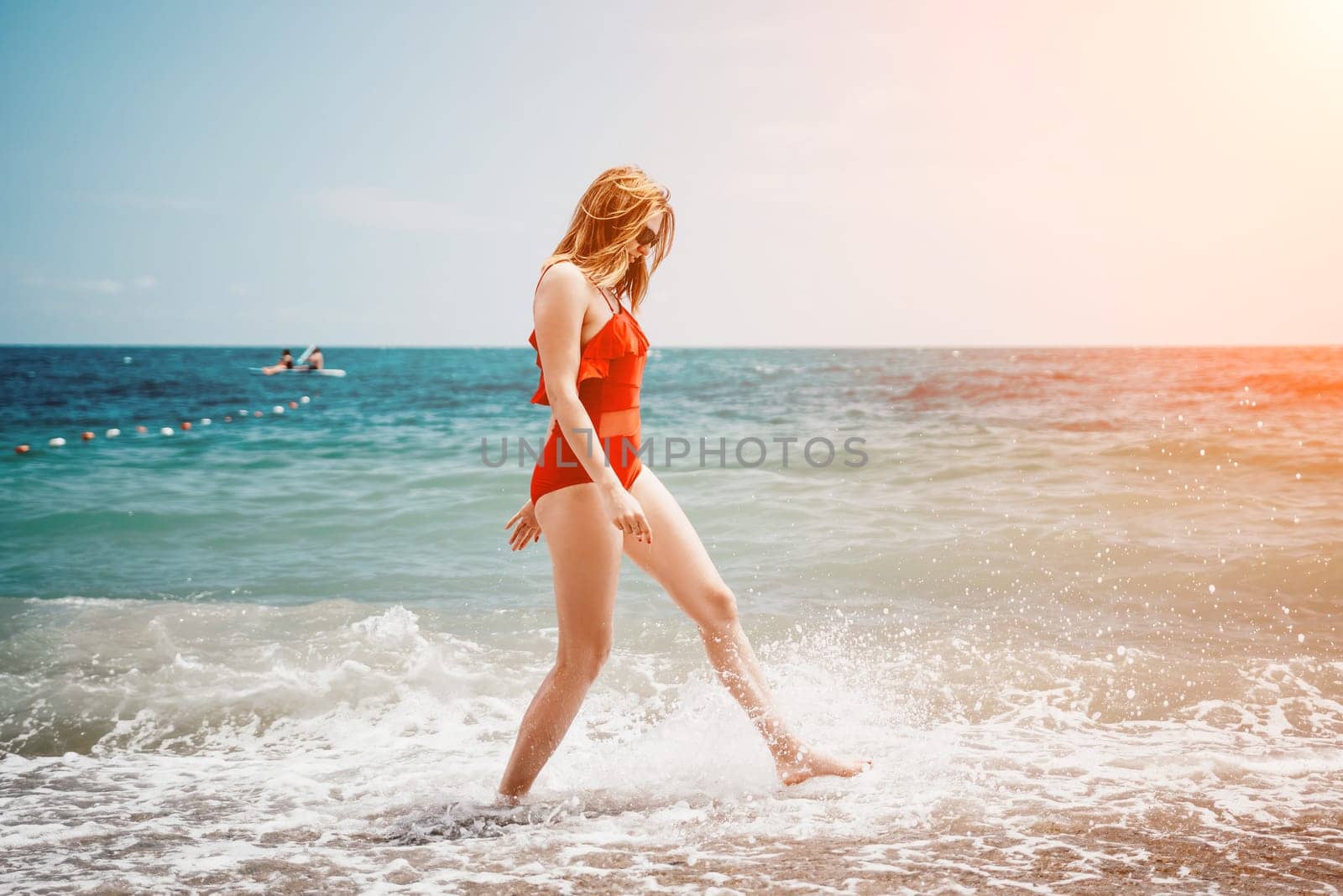 Pretty young blonde woman walking on the beach in summer, having fun, walks carefree on the seaside . Portrait beautiful young woman relax smile around beach sea ocean in holiday vacation travel trip.