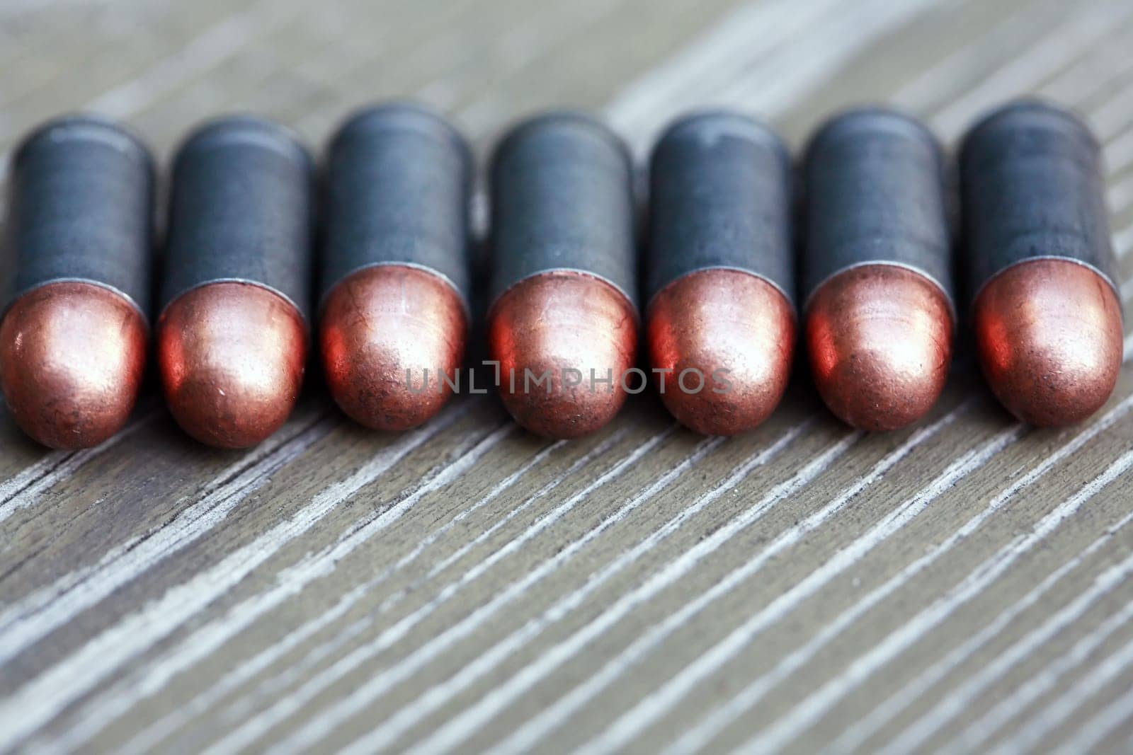 Closeup of few pistol bullets in a row on old wooden background