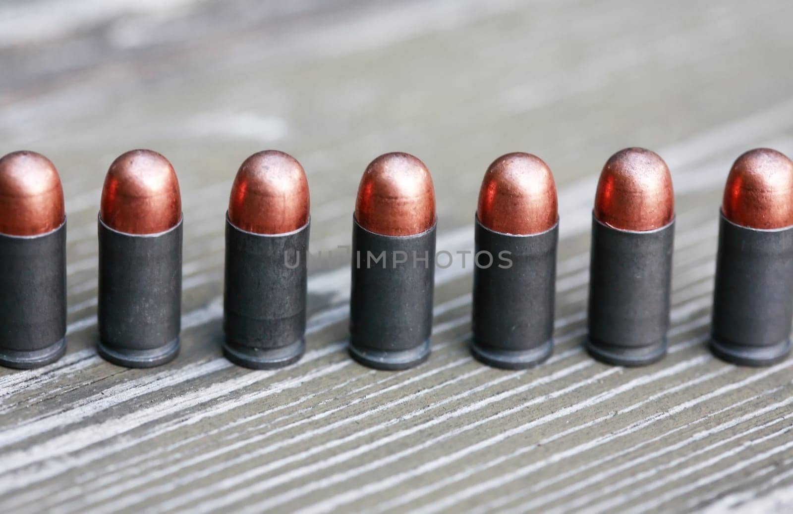 Closeup of few pistol bullets in a row on old wooden background