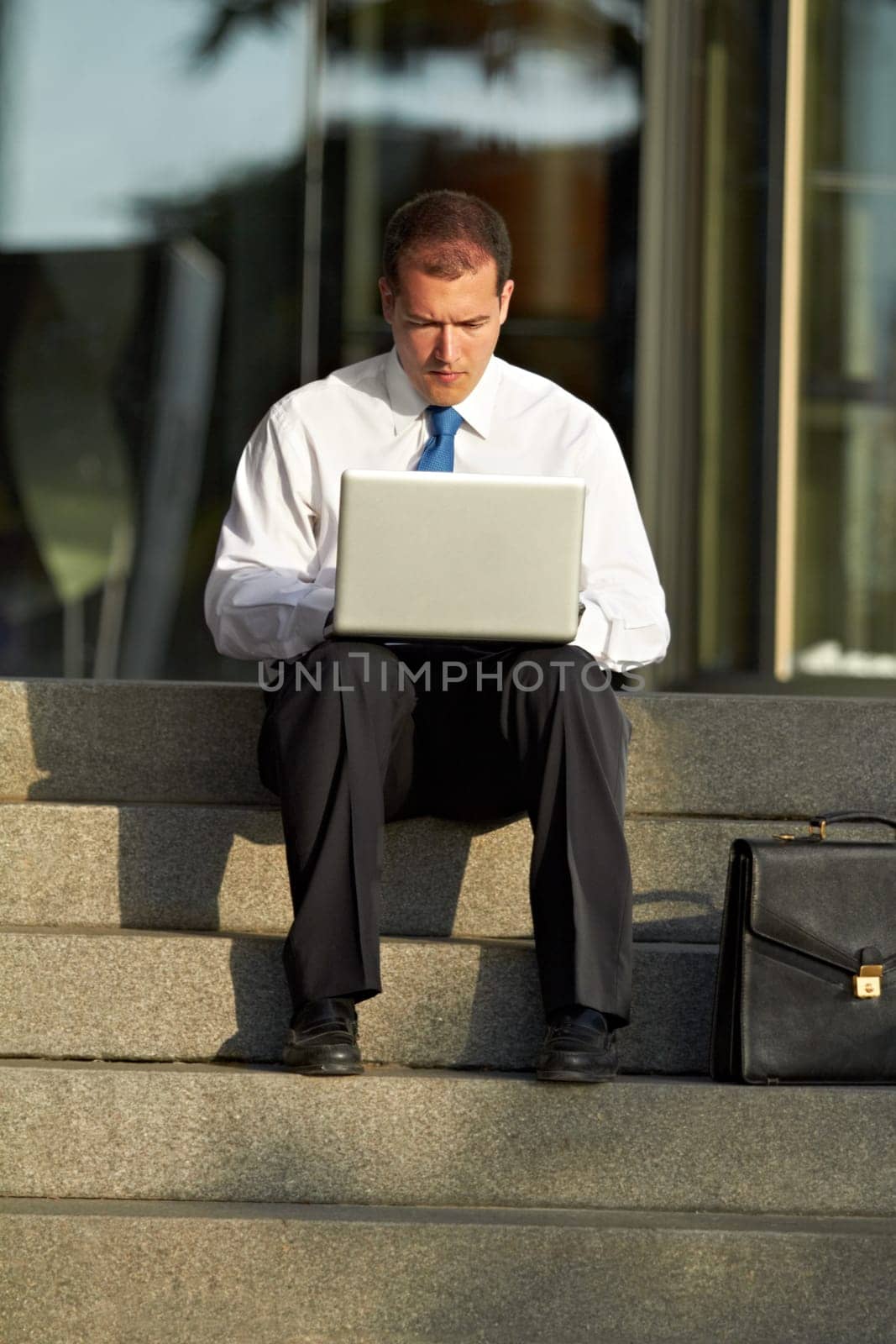Accounting, businessman with laptop and focus on staircase for remote work. Online communication or connectivity, deadline or social networking and serious or worried man working on financial report by YuriArcurs