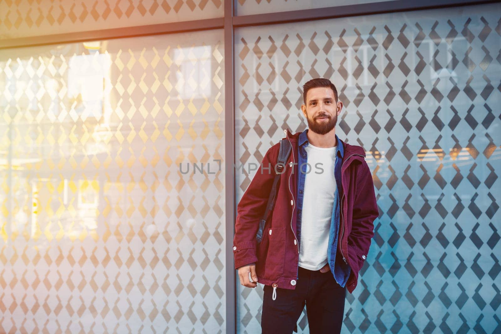 Street fashion model tourist man outdoor. Waiting friends on grunge wall. Man wearing black bag and purple jacket, autumn.