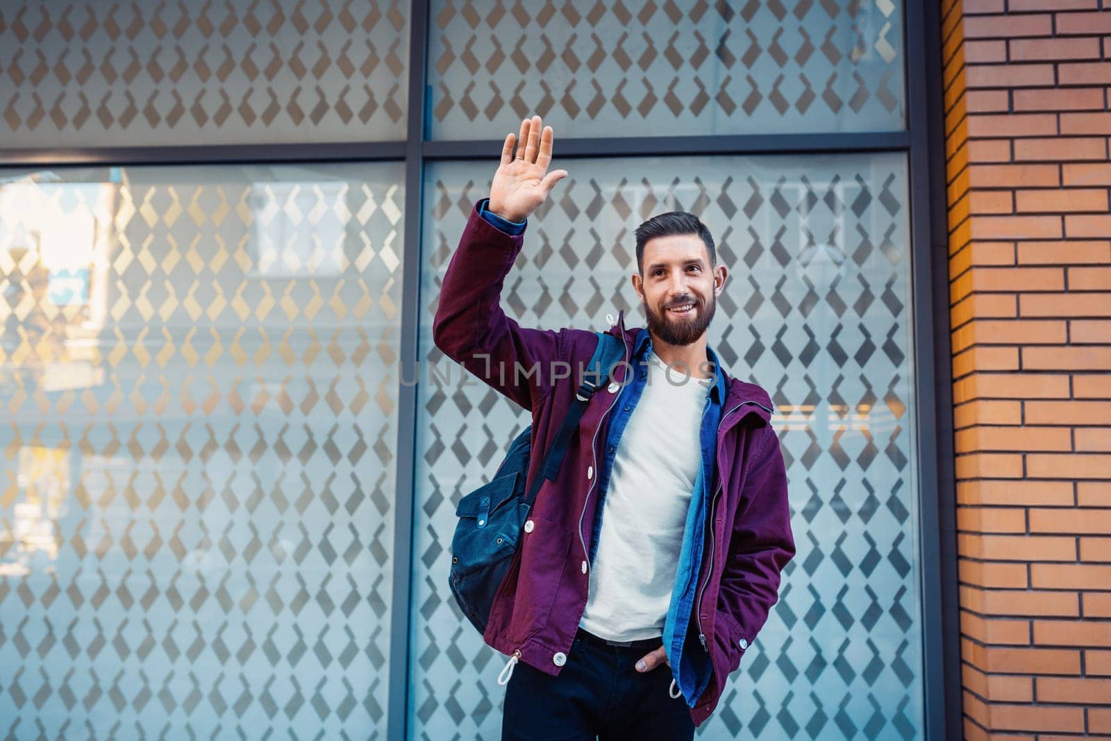 Street fashion model tourist man outdoor. Waiting friends on grunge wall. Man wearing black bag and purple jacket, autumn.