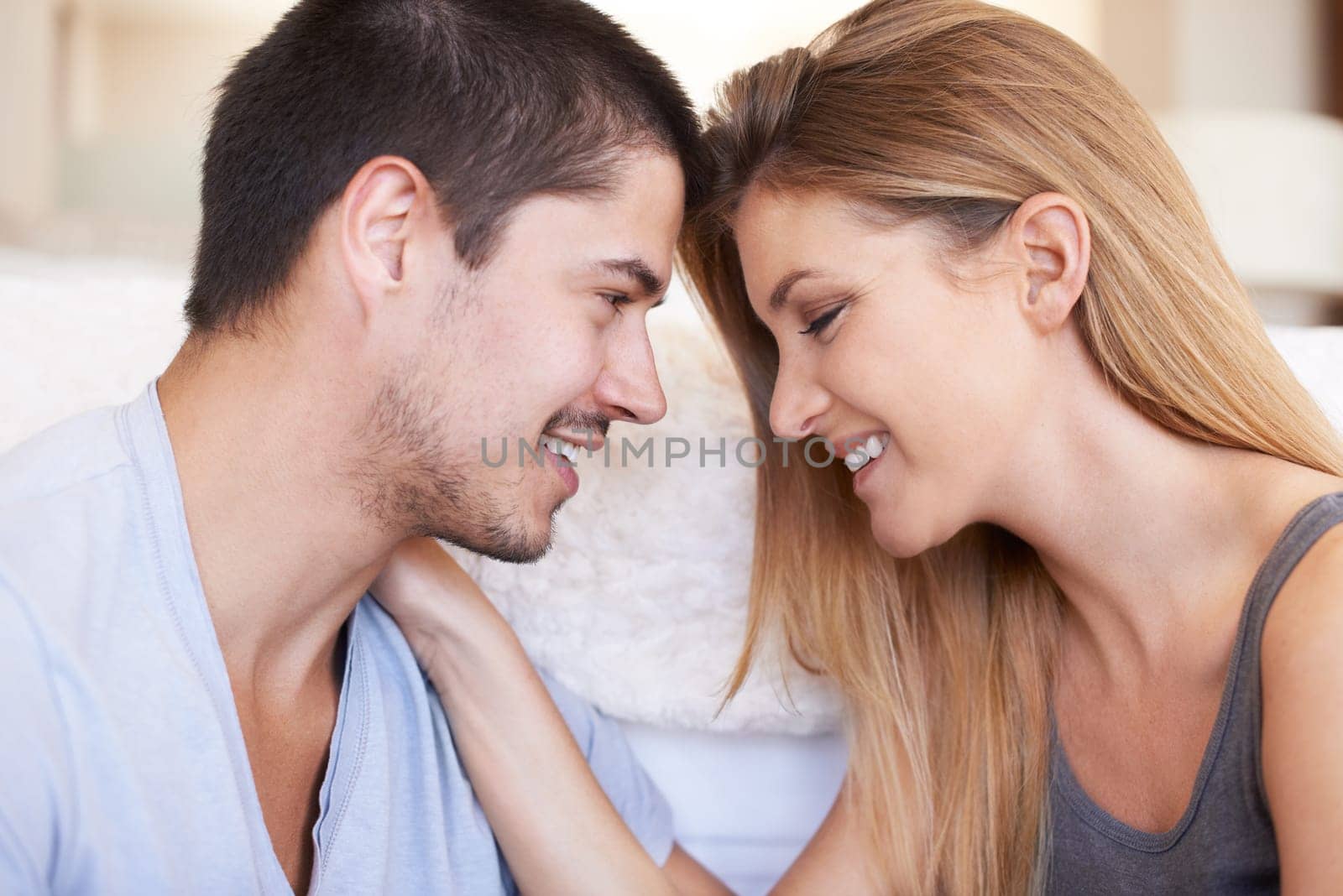 Face, intimacy and couple relax and bond in a living room happy, sweet and sharing romance in their home together. Smile, embrace and woman with man in a lounge for conversation, love and hangout by YuriArcurs