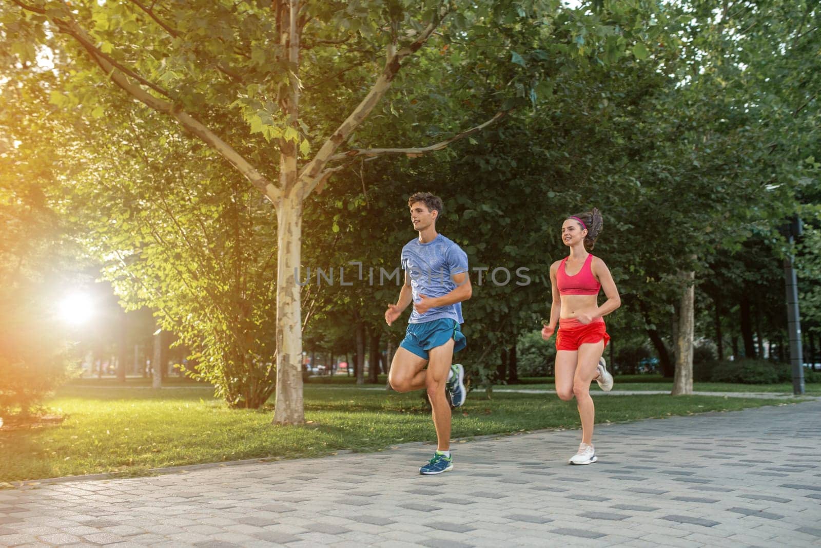 Portrait of cheerful caucasian couple running outdoors. Sun flare.