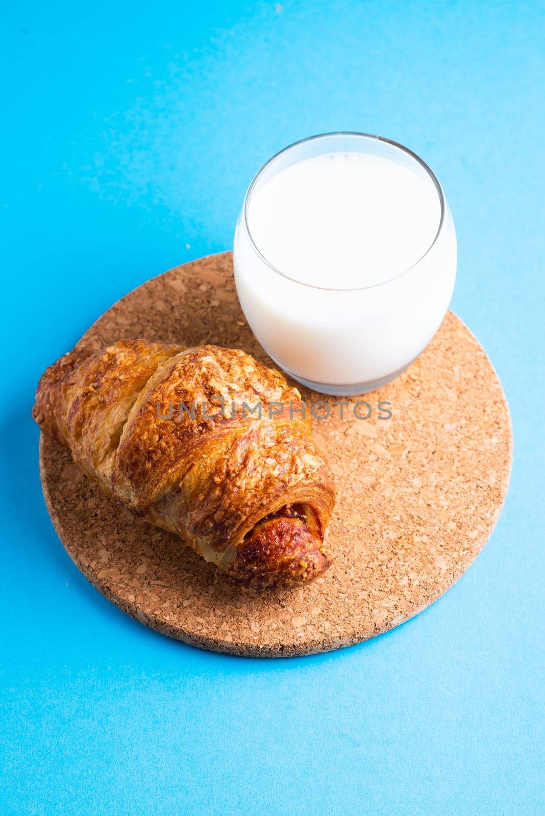 Breakfast bread and cup of milk on yellow and blue background