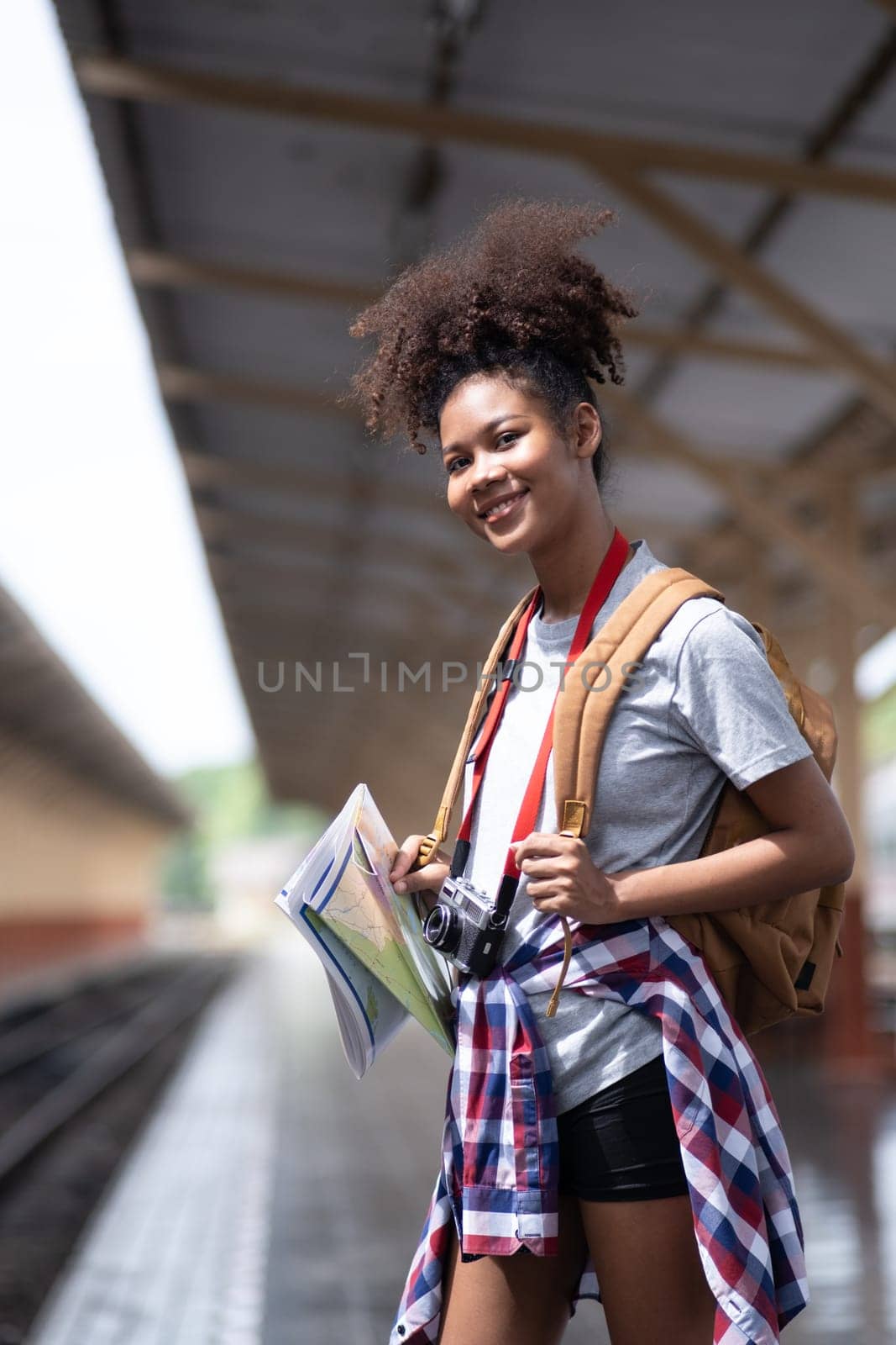 Young Asian African woman traveler with backpack in the railway train, traveler girl walking stand sit waiting take a by wuttichaicci