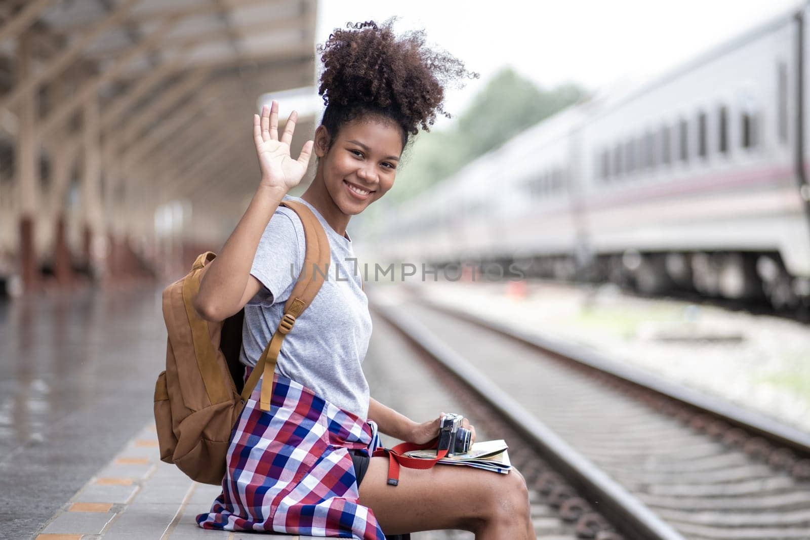 Young Asian African woman traveler with backpack in the railway train, traveler girl walking stand sit waiting take a by wuttichaicci