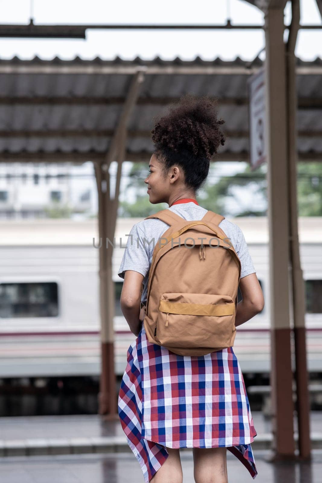 Young Asian African woman traveler with backpack in the railway train, traveler girl walking stand sit waiting take a by wuttichaicci