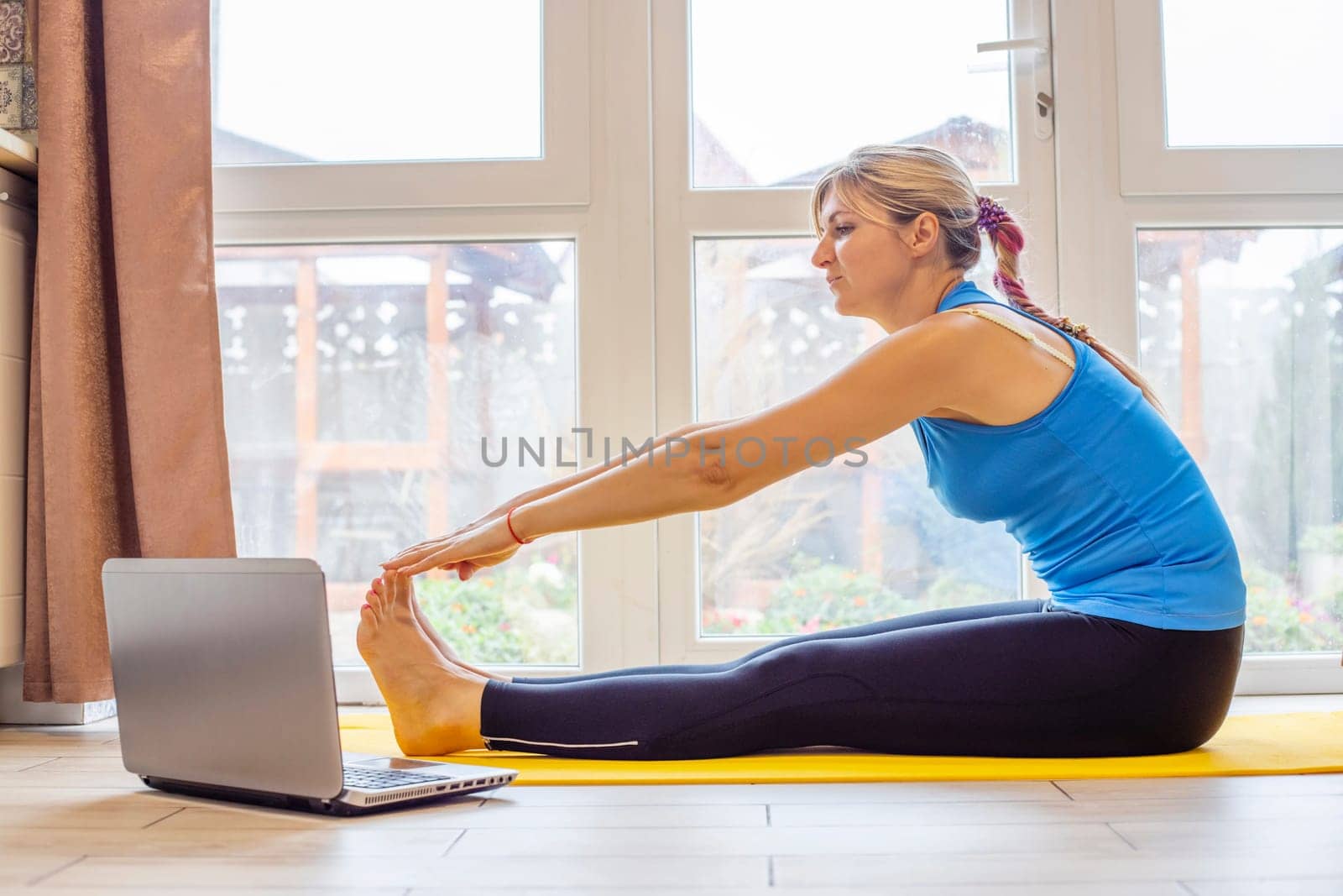 Beautiful young woman in sportswear doing sport exercises on yoga mat at home by andreyz