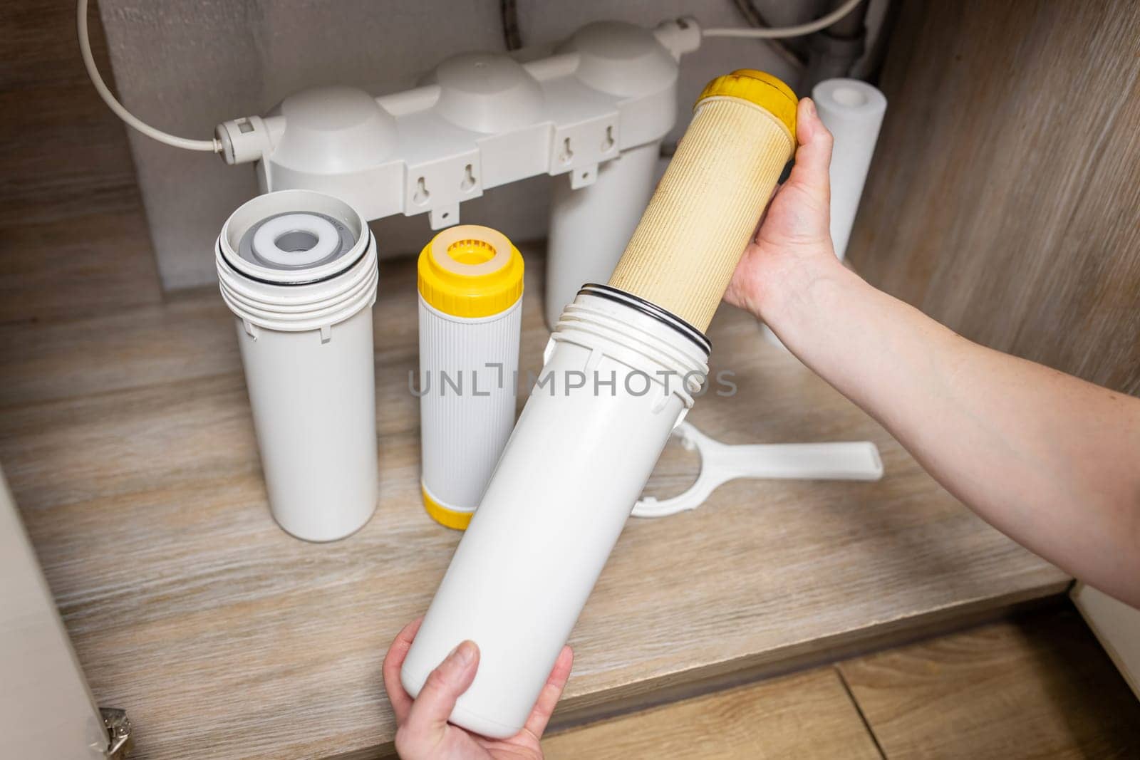 Plumber installs or change water filter. Replacement aqua filter. Repairman installing water filter cartridges in a kitchen. Clean water at home.