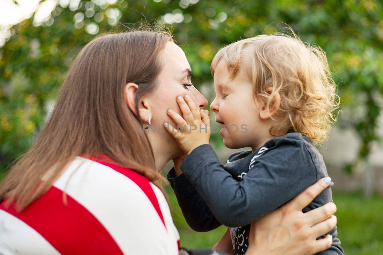 Happy mother and son hugging in love playing in the park.