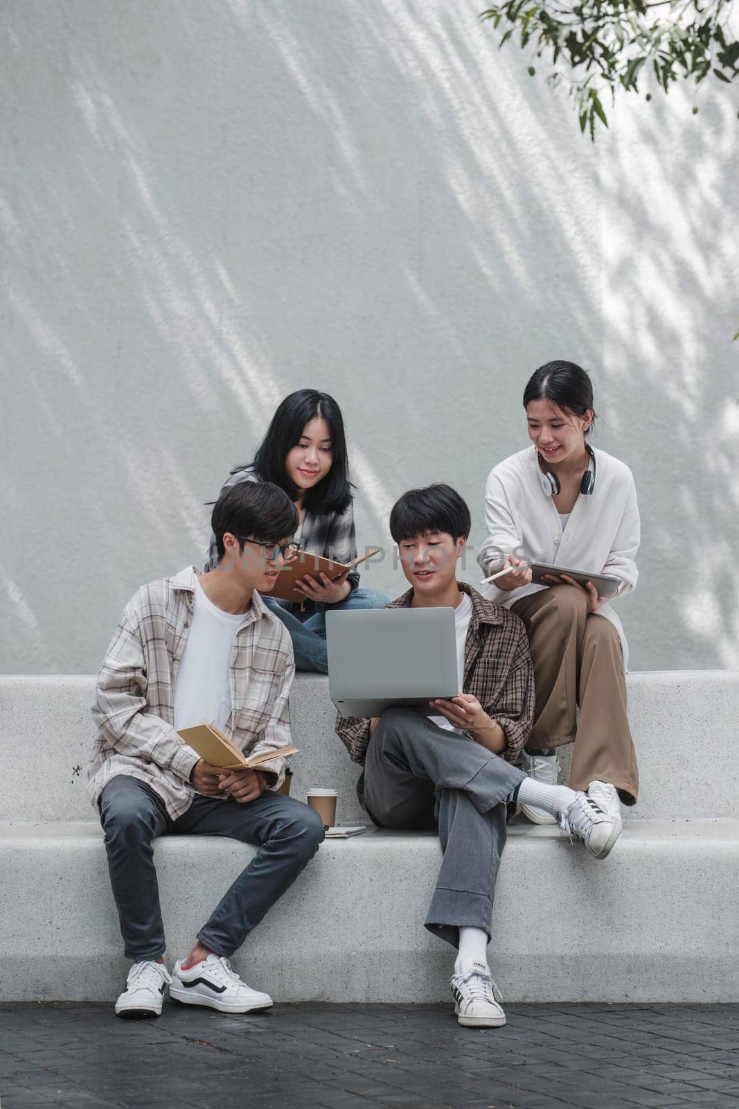 Group of Asian college student reading books and tutoring special class for exam on grass field at outdoors. Happiness and Education learning concept. Back to school concept. Teen and people theme. by wichayada