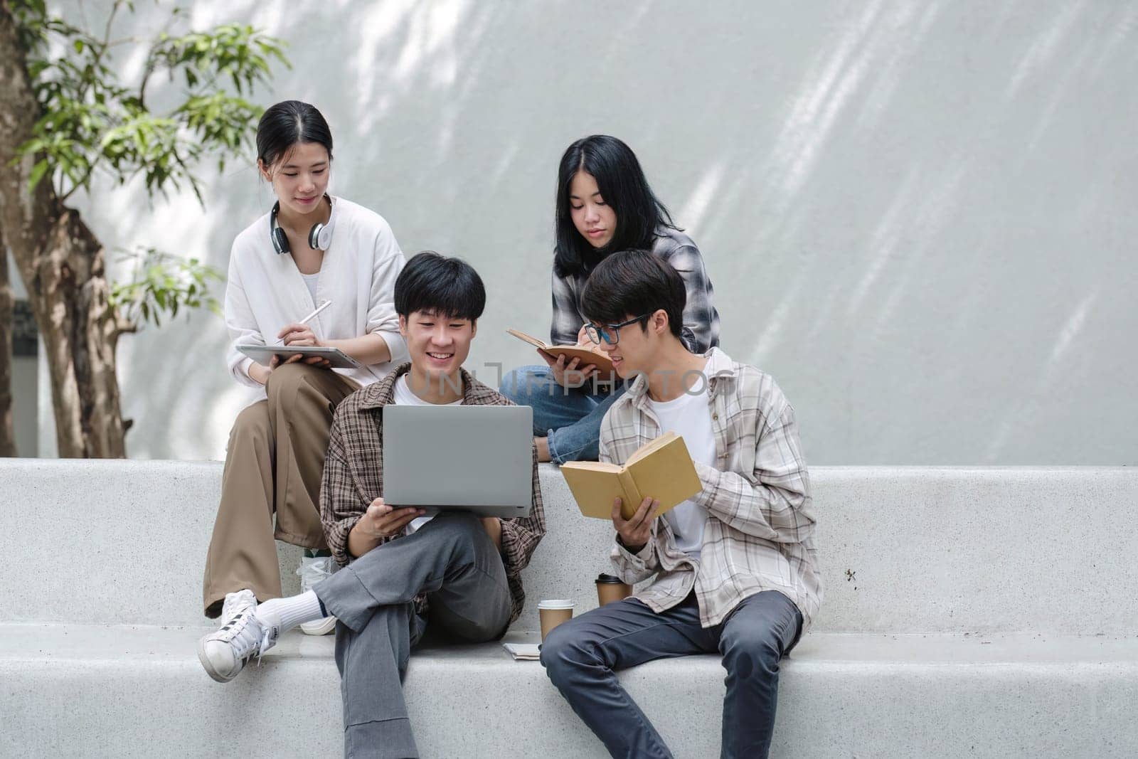 Group of Asian college student reading books and tutoring special class for exam on grass field at outdoors. Happiness and Education learning concept. Back to school concept. Teen and people theme...