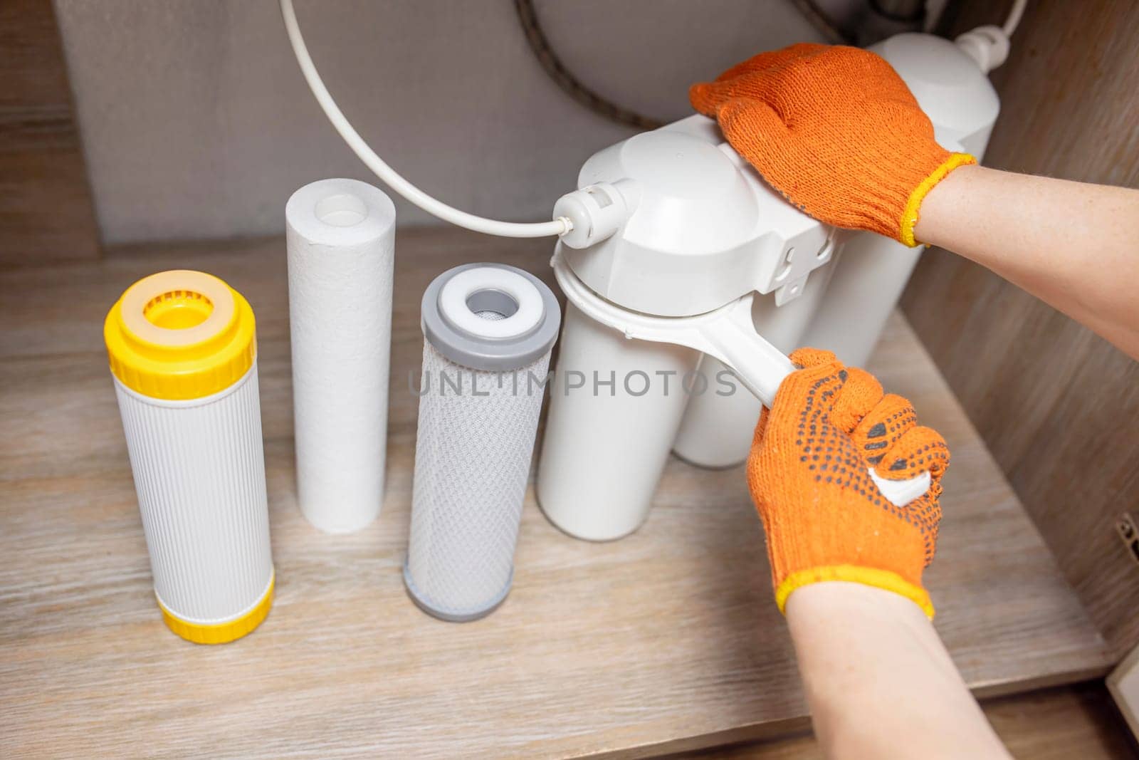 Plumber installs or change water filter. Replacement aqua filter. Repairman installing water filter cartridges in a kitchen. Clean water at home.