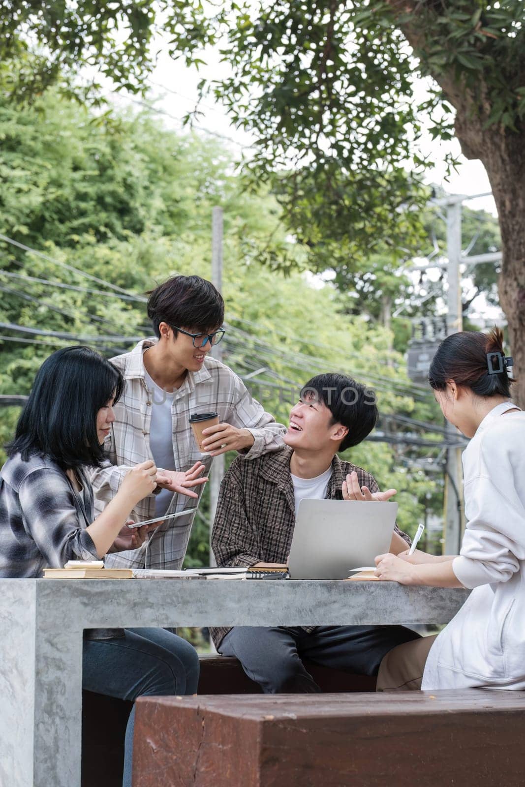 Group of Asian college student reading books and tutoring special class for exam on grass field at outdoors. Happiness and Education learning concept. Back to school concept. Teen and people theme. by wichayada